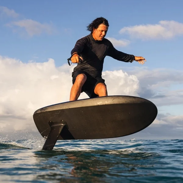 Fliteboard Ultra L3 - Lifestyle Image 7 Surfer riding a carbon Fliteboard Ultra L3 electric hydrofoil over ocean waves.