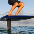 A person riding a ultramarine Fliteboard Ultra L3 electric hydrofoil surfboard above the ocean waves.