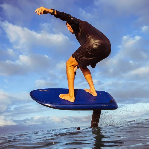 Fliteboard Ultra L3 - Lifestyle Image 8 A person riding a Ultramarine Fliteboard Ultra L3 eFoil above ocean waves at sunset.